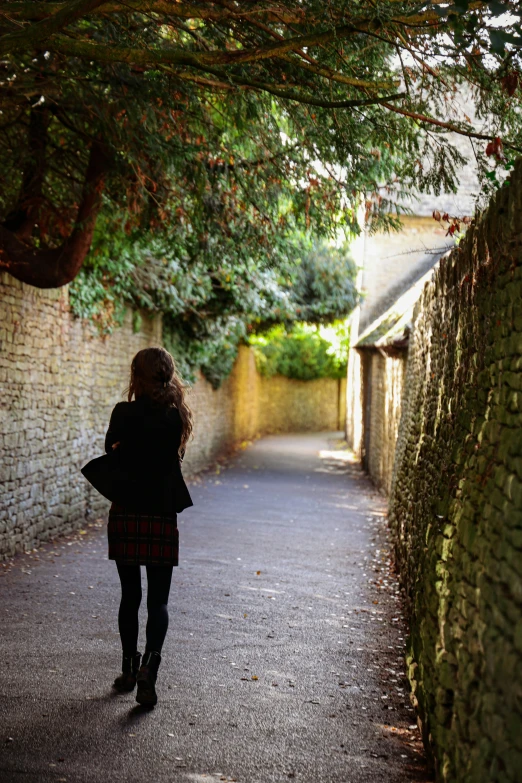 a woman walks down a narrow street by some brick buildings