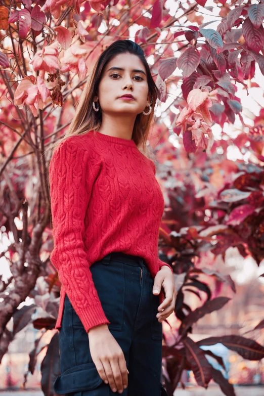 a woman is standing near a tree while looking up