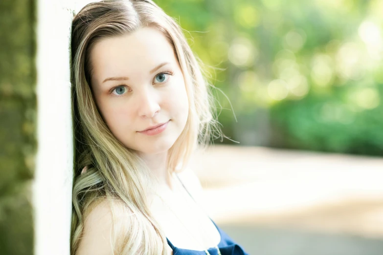 a woman wearing a blue shirt standing under a tree