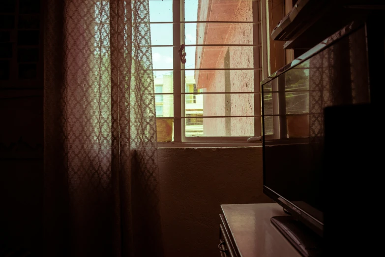 the view outside of a window shows green, white and red curtains
