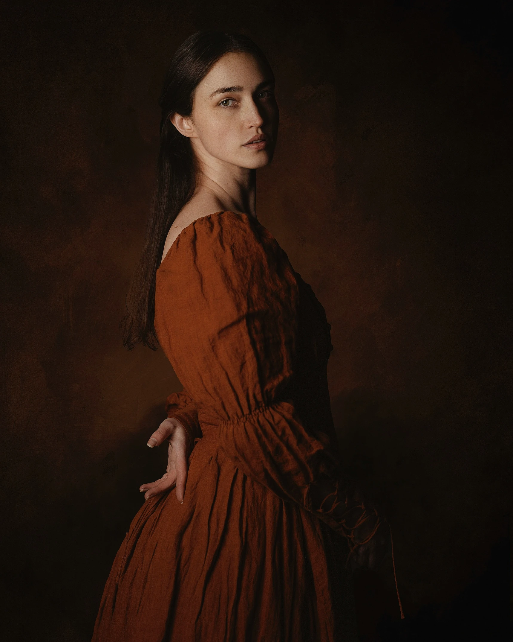 woman in red dress standing against dark wall