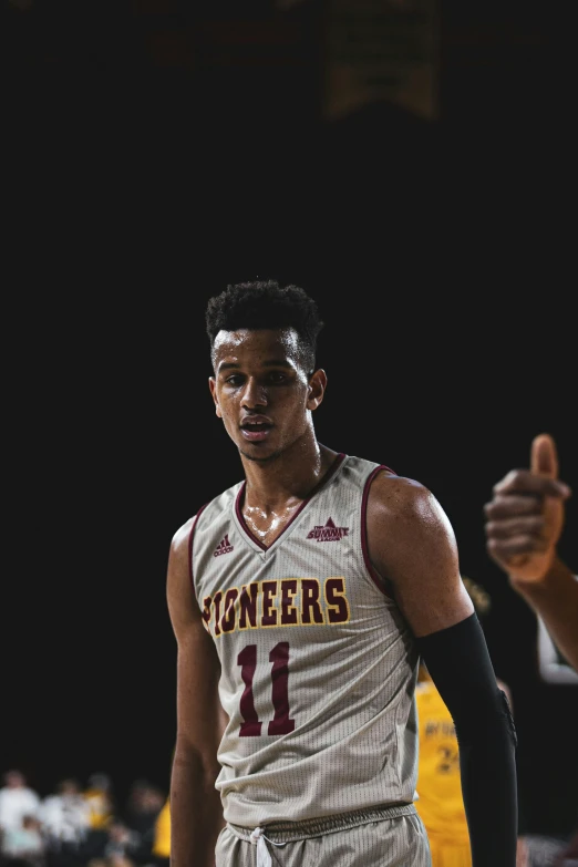 a man standing in a basketball uniform while giving a thumbs up