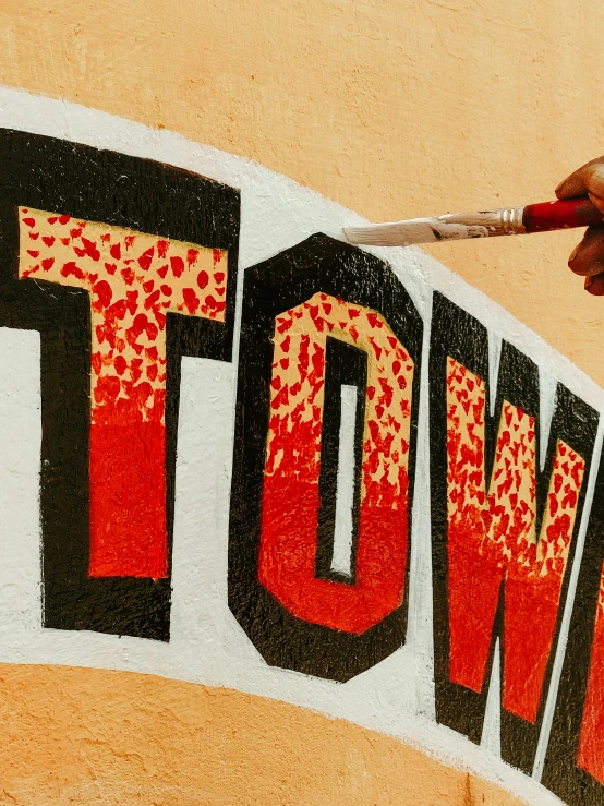 a hand is painting the letters for a town