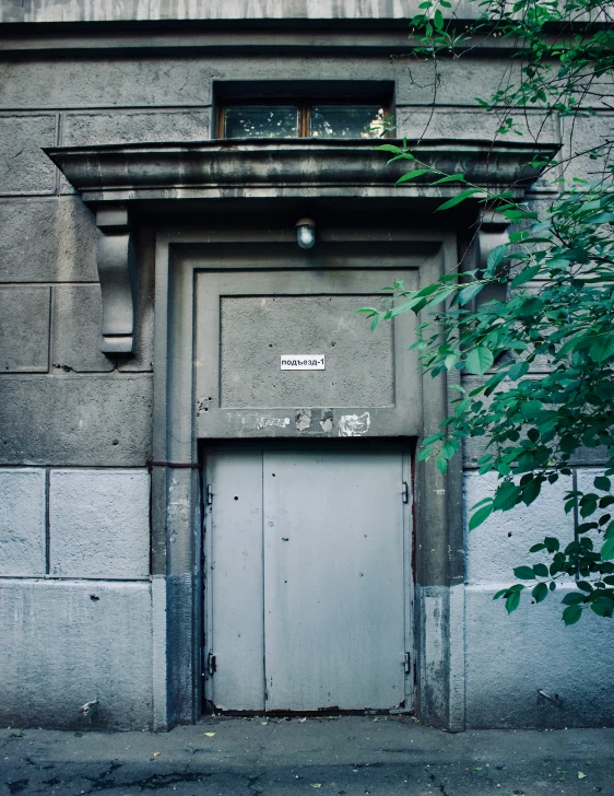 an old grey door with green leaves near a building