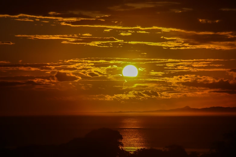 a very bright sun setting above some water