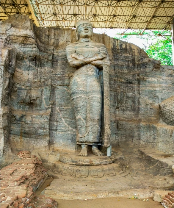 an ancient statue under a roof next to a wall