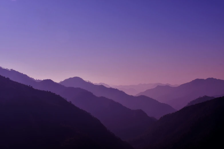 a mountain range is shown at dusk with purple clouds