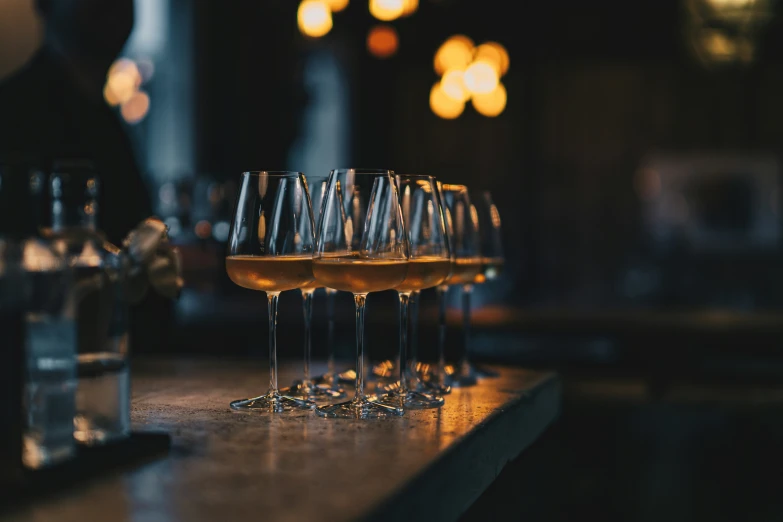 a table with several glasses of wine next to two bottles