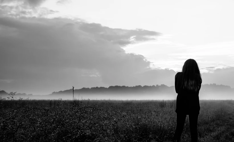 a black and white po of a woman standing in a field with a fog