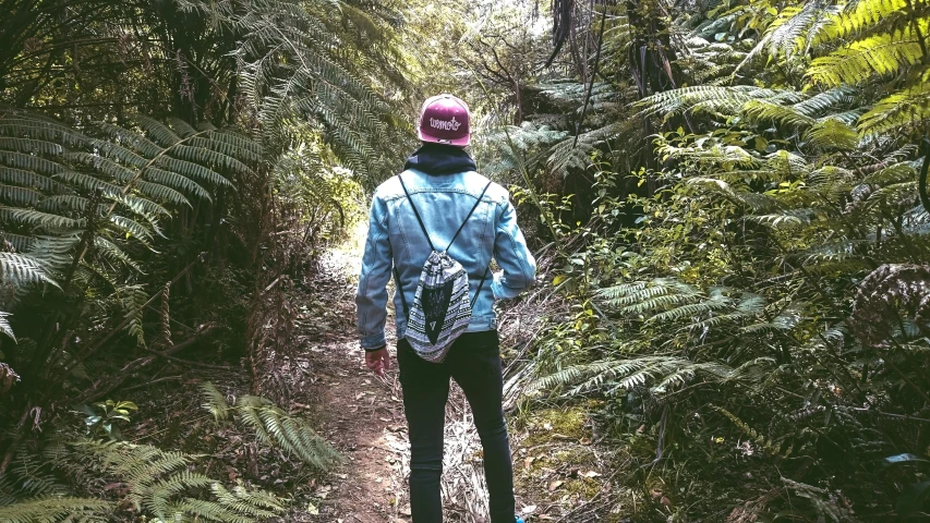 the man in a helmet is walking down a trail through the woods