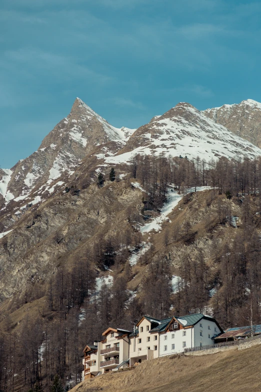 a mountain has several buildings and trees in front