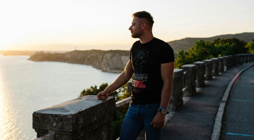 a man in a black shirt is standing near a large river