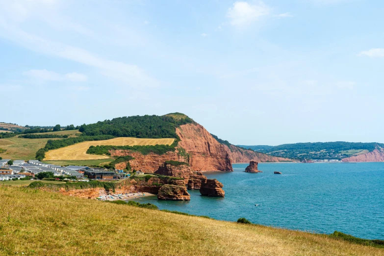 a green field next to a hill and the water