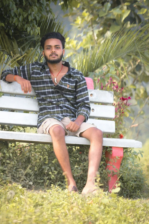 a man sitting on top of a white wooden bench