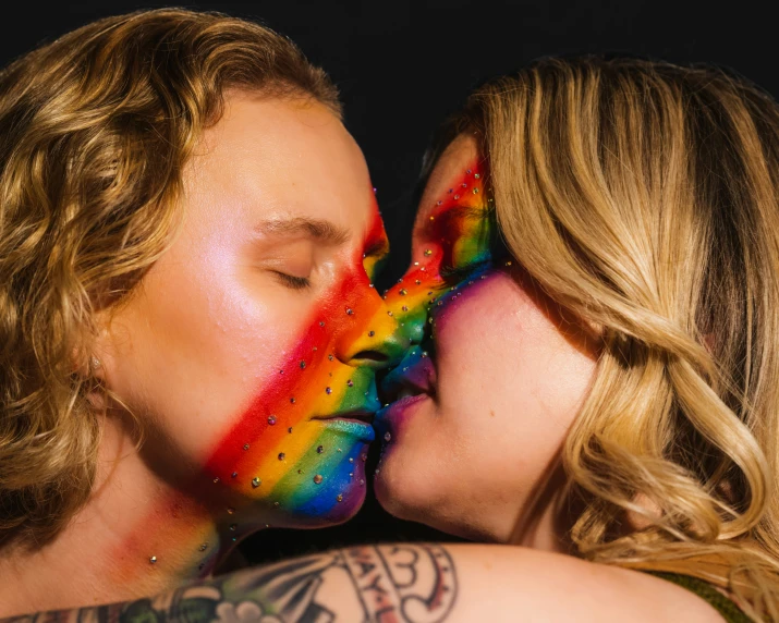 a couple kissing while one woman painted like a rainbow