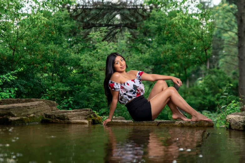 a woman sitting on a stone with water