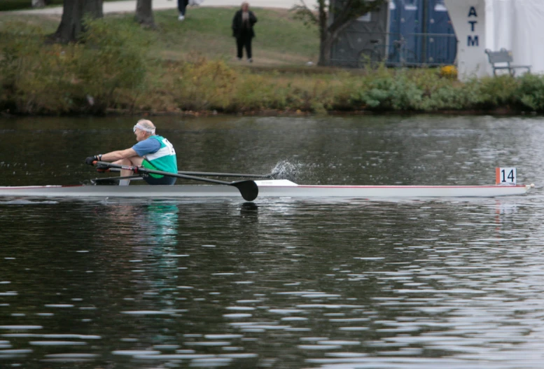 an elderly man sits on a rowing boat, and looks across the river