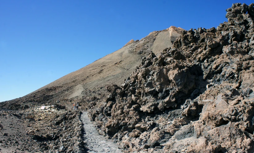 a long trail going down a cliff with large rocks on the side