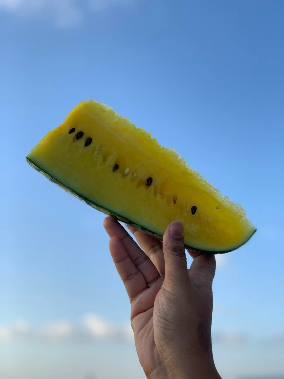 a hand holding a slice of a yellow banana