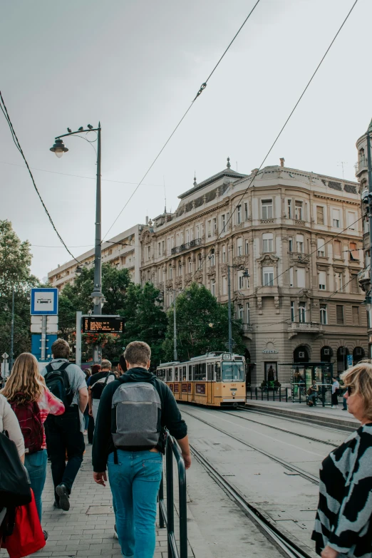 people walking down the sidewalk next to trains