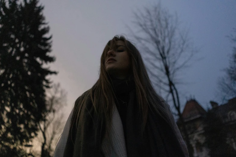 a woman in a fur coat standing next to trees