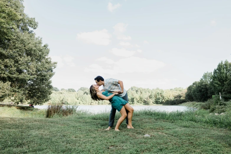 two young people on the grass and one kissing each other