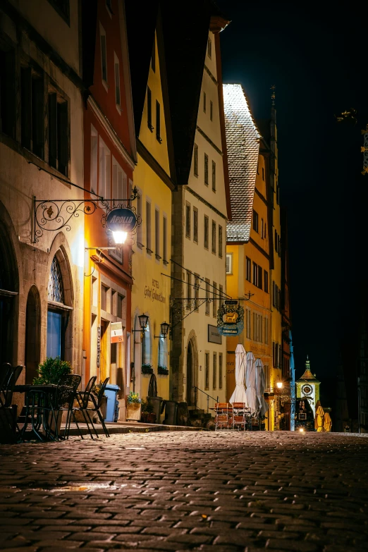 an empty brick street at night with many small businesses