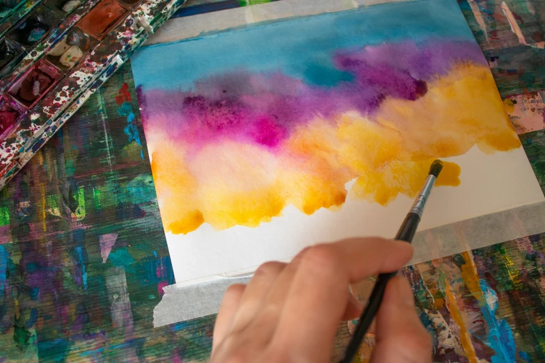 a painting being drawn on paper next to paint and brushes