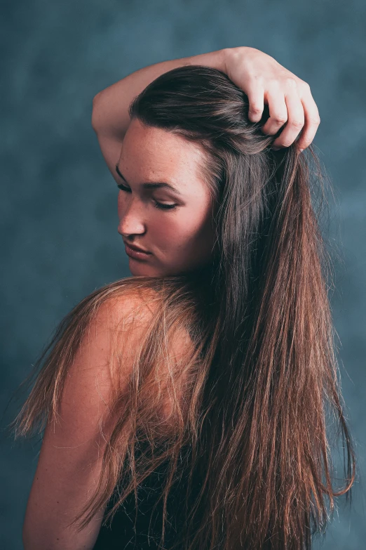 a beautiful woman with long hair standing next to a blue wall