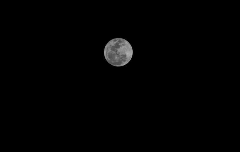 a lone plane flying in front of the moon