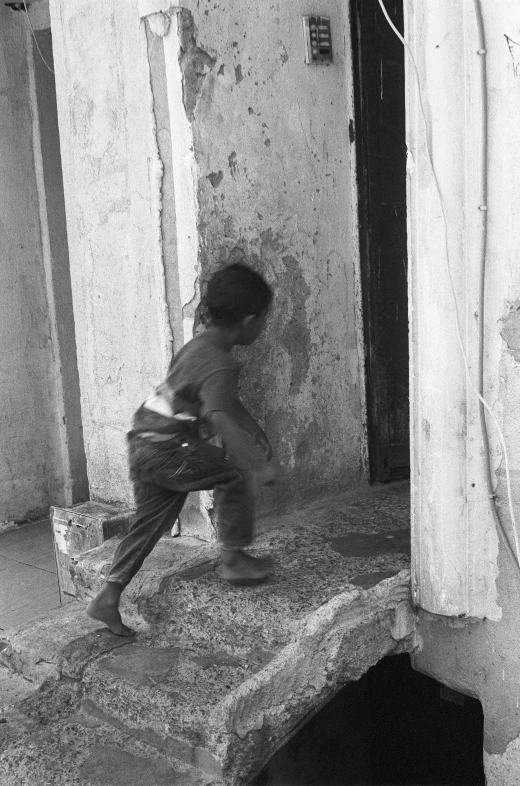 a boy walking down a sidewalk next to the door