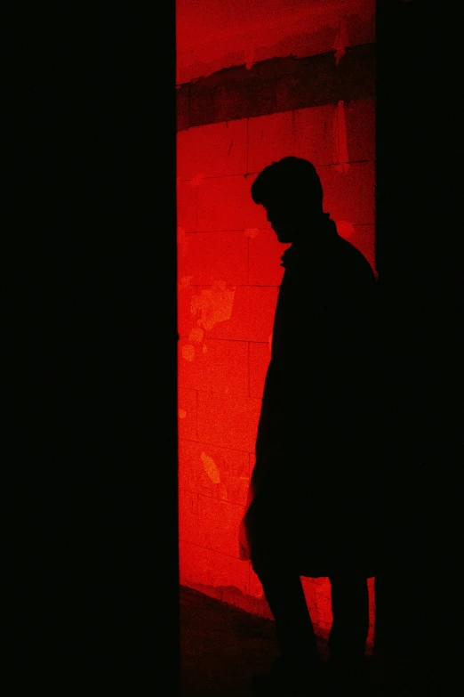 the dark silhouette of a man looking into a large red box