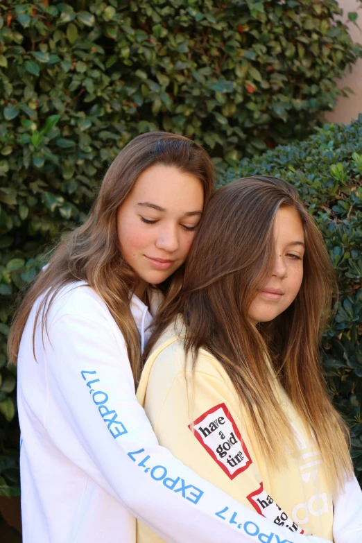 two girls, one with long hair, emcing while holding each other