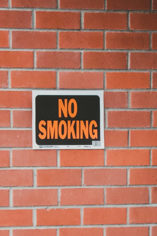 there is a no smoking sign attached to a brick wall