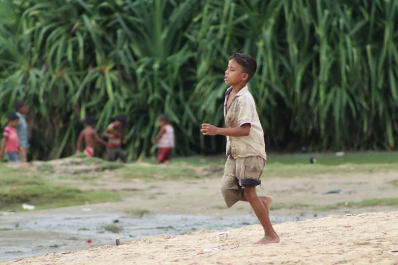 a boy standing on a sand hill near water