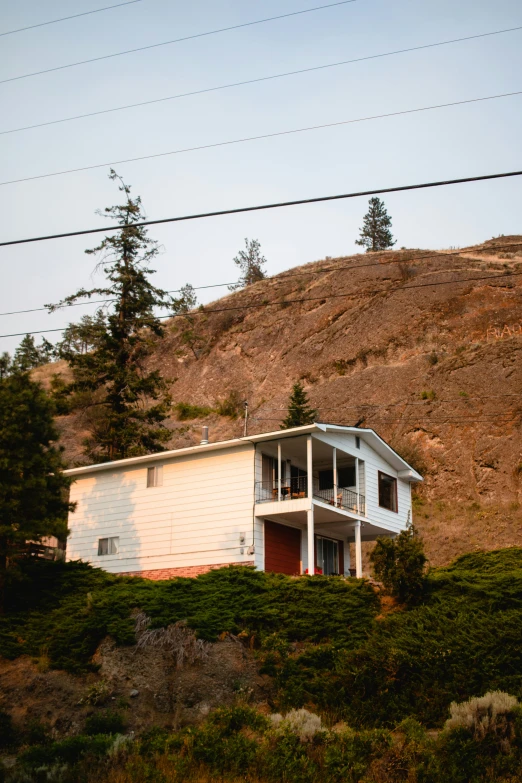 a white house next to a hill under a line of power lines