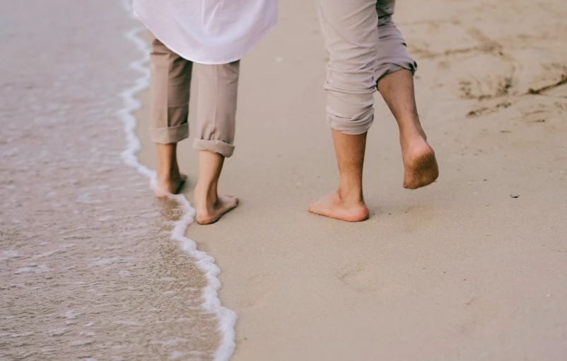 a couple of people walking on top of a beach