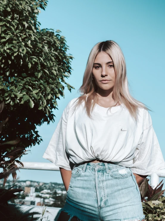 a woman with blonde hair standing next to a tree