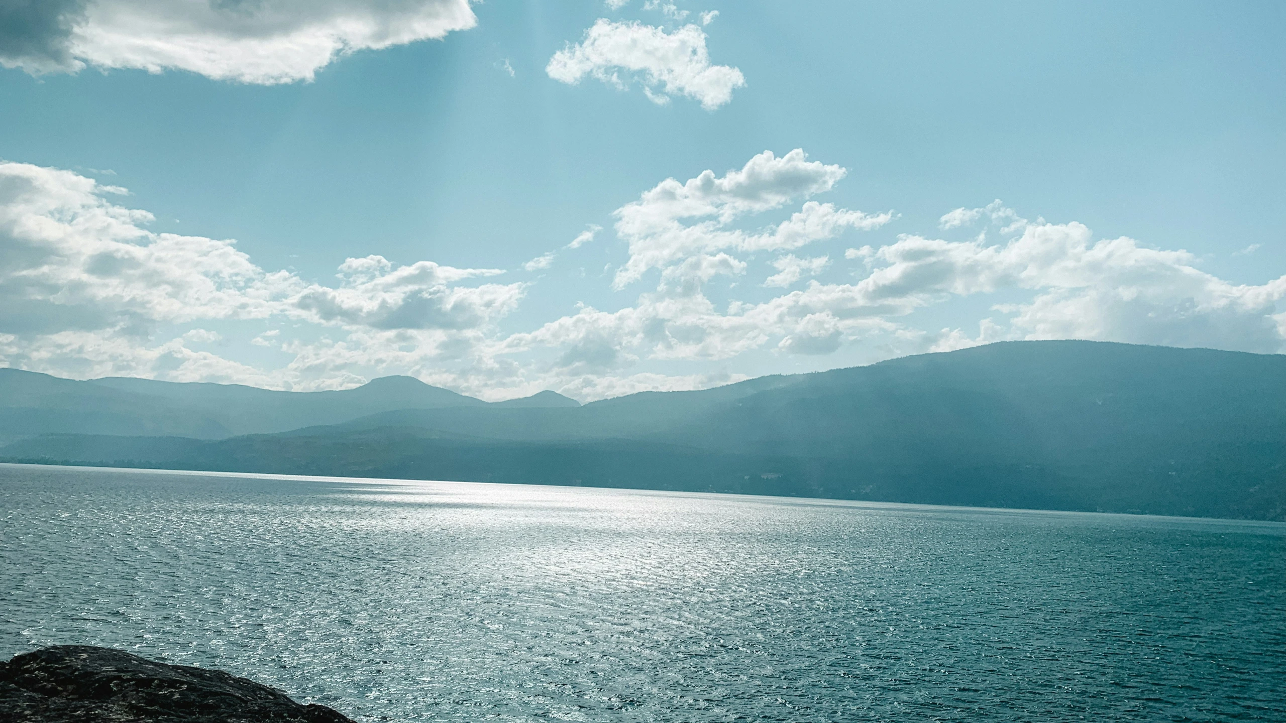 a body of water surrounded by hills and clouds