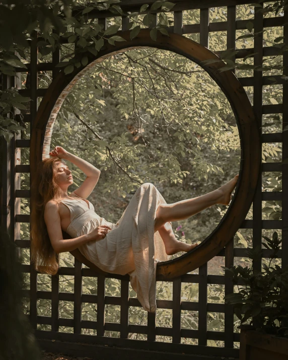 a woman laying in a circular swing, in the park