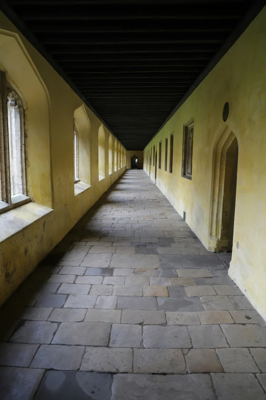 a brick walkway has windows and doors along both sides