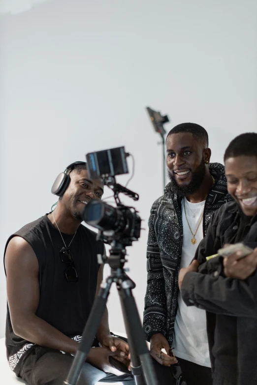 three guys are filming a camera and smiling