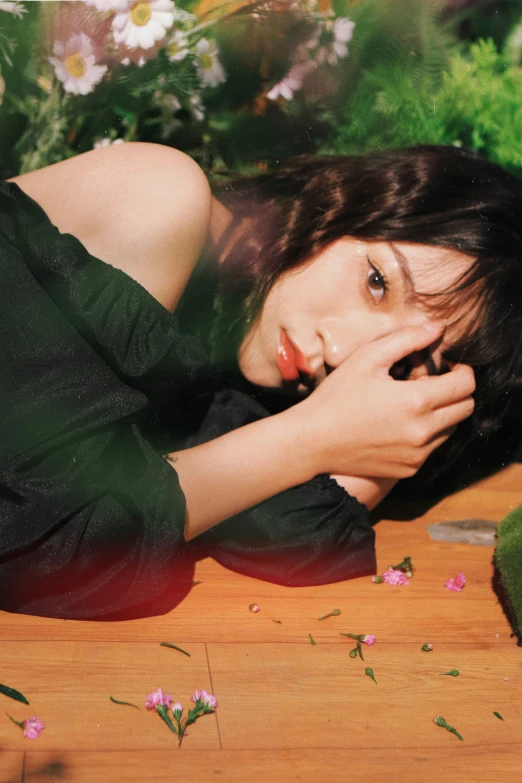 a girl is posing by some flowers on the ground