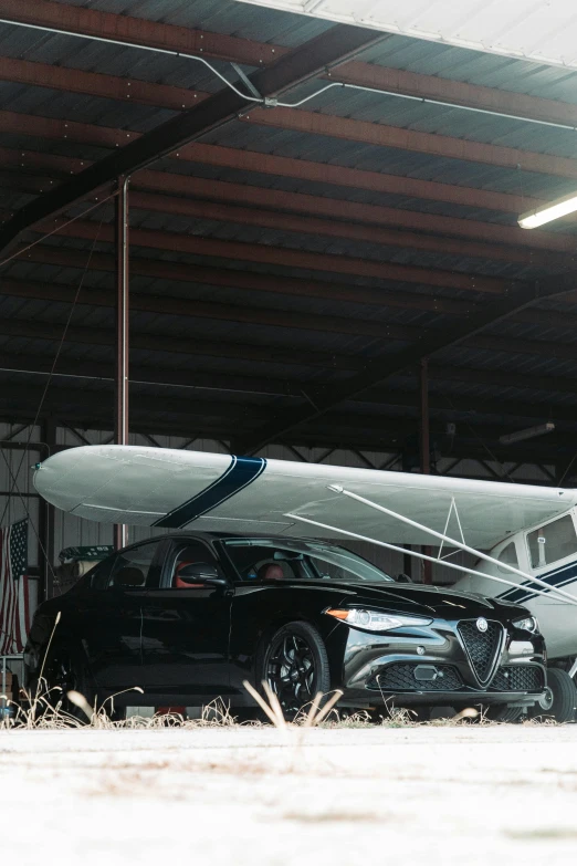 a sports car is parked in a garage with an airplane and a jet