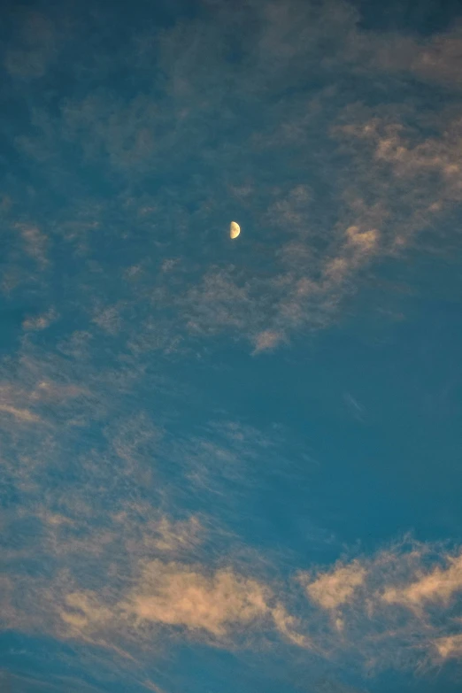 the moon is in the sky with some clouds