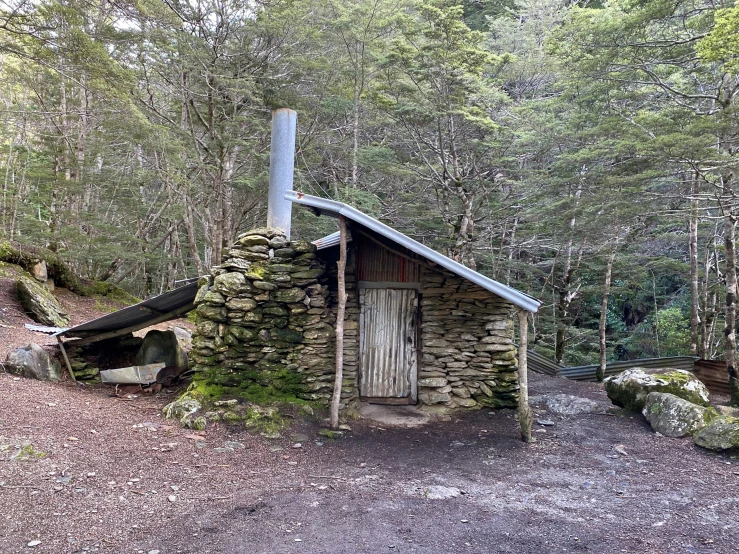 an old stone building in the woods by itself