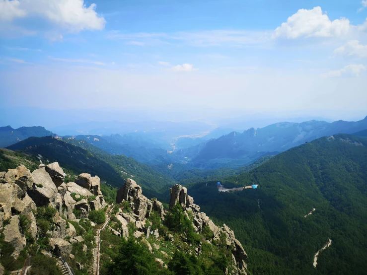 green, mountain landscape overlooking valley, in the distance is blue sky and white clouds