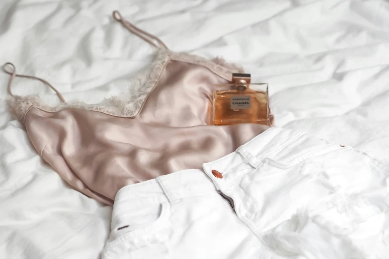 an underwear and perfume bottle on a bed