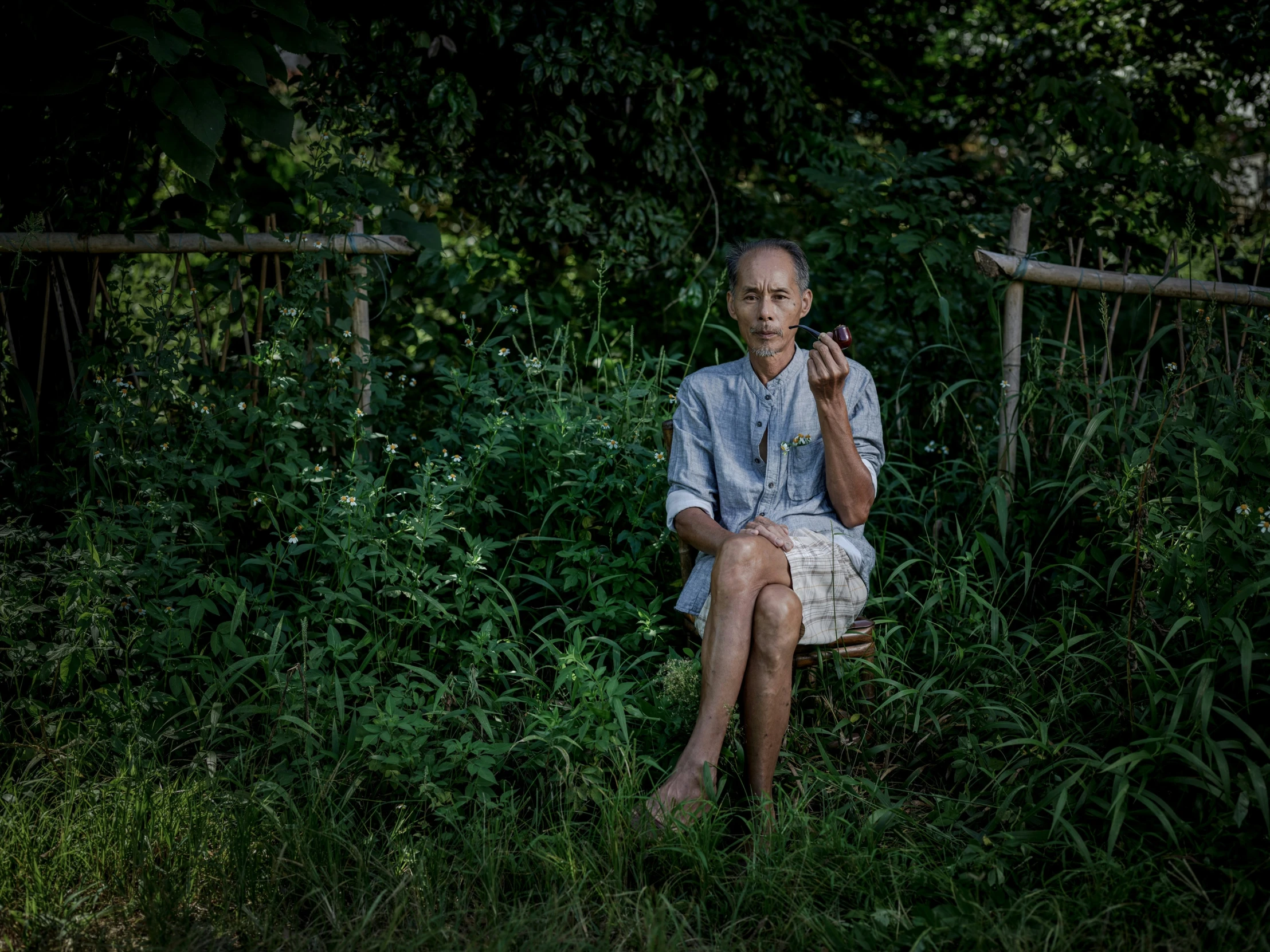 a person sitting down in the grass while smoking a cigarette