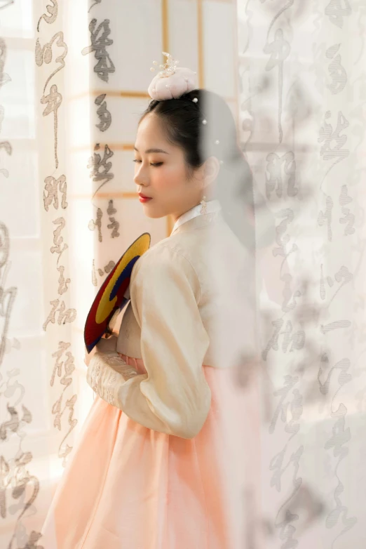 woman in a white and orange oriental dress looking out of the window